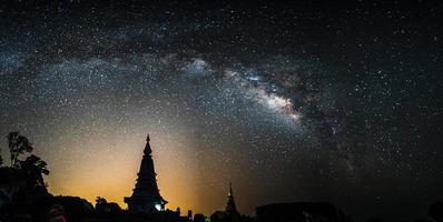Via Láctea à noite acima da silhueta do pagode na Tailândia. foto