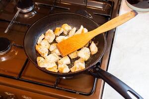 frango seios carne só em fritar panela e de madeira espátula, doméstico saudável cozinha, real vida situação. foto