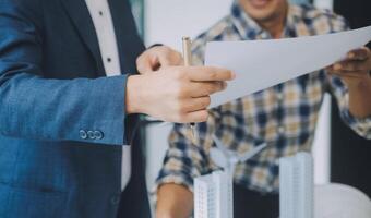 conceito de construção e estrutura de reunião de engenheiro ou arquiteto para projeto trabalhando com parceiros e ferramentas de engenharia na construção de modelo e projeto no local de trabalho, contrato para ambas as empresas. foto