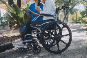 enfermeira com idosos homem dentro cadeira de rodas às parque foto