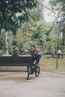 feliz ásia jovem mulher andar e passeio bicicleta dentro parque, rua cidade dela sorridente usando bicicleta do transporte, eco amigável, pessoas estilo de vida conceito. foto