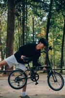 bonito feliz jovem homem com bicicleta em uma cidade rua, ativo estilo de vida, pessoas conceito foto