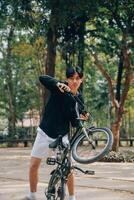 bonito feliz jovem homem com bicicleta em uma cidade rua, ativo estilo de vida, pessoas conceito foto