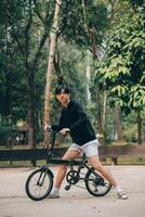 bonito feliz jovem homem com bicicleta em uma cidade rua, ativo estilo de vida, pessoas conceito foto