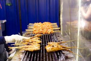 grelhado frango e carne de porco em a fogão fogão em tailandês rua mercado Comida estilo foto