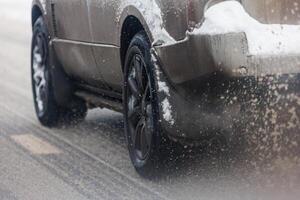 estrada neve peças fluxo a partir de rodas do sujo carro acelerando dentro luz do dia cidade com seletivo foco. foto