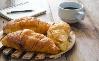 croissants café caderno e lápis em a de madeira mesa - tom vintage foto