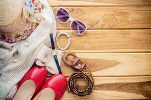 acessórios para Adolescência menina em dela férias, chapéu, à moda para verão oculos de sol, sapatos e traje em de madeira chão. foto