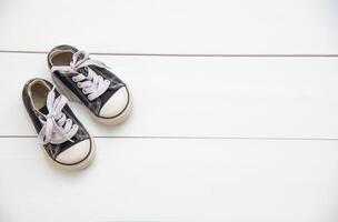 Preto sapatos para crianças em de madeira chão foto