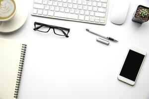 topo Visão com cópia de espaço, trabalhando escrivaninha com laptop, celular telefone, notebook lápis e café em branco fundo foto