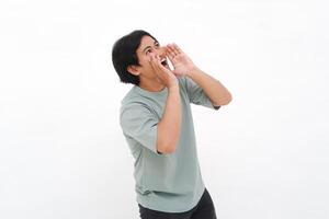 uma jovem ásia homem empregado vestindo camiseta é gritando e gritando alto com uma mão em dela boca, isolado de branco fundo. foto