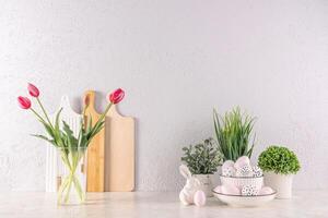 festivo cozinha fundo para Páscoa dia. elementos do Páscoa decoração, flores dentro uma vaso e potes, ovos e Coelho em a cozinha bancada. foto