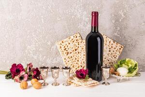 festivo ainda vida para a Primavera judaico feriado do páscoa. tradicional kosher comida, uma garrafa do vermelho vinho e prata tiro óculos com derramado vinho. foto