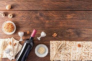 tradicional guloseimas para a judaico feriado do Páscoa em uma de madeira Vila mesa. garrafa do vermelho vinho, matzote, fruta colar . topo visualizar. foto