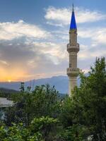mesquita torre dentro uma Vila durante dourado hora pôr do sol foto