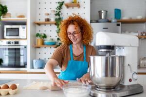 feliz atraente jovem adulto mulher dona de casa padeiro vestem avental segurando PIN rolando massa em cozinha mesa cozimento pastelaria conceito cozinhando bolo bolacha fazendo padaria fazer caseiro pizza às casa foto