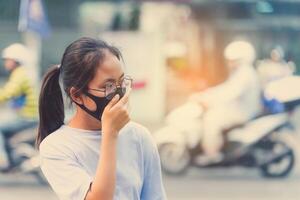 menina vestindo uma Preto narizes n95 pano para evita poeira PM 2,5 que tem uma muito Alto valor dentro uma cidade com tráfego foto