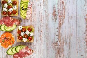 a sortimento do sanduíches com peixe, queijo, carne e legumes deitar em a de madeira mesa foto