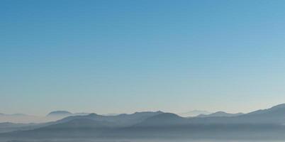 enevoado Largo colinas panorama com azul céu negativo espaço. foto