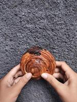 mãos segurando cromboloni, volta croissant, Novo Iorque rolar, uma viral pastelaria combinando croissants e bomboloni em concreto parede fundo. foto