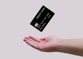 homem mão e Preto crédito cartão brincar flutuando, usava para conectados compras e conectados transações. isolado em cinzento fundo foto