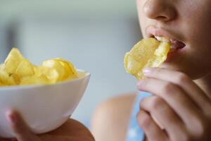 colheita Adolescência menina comendo crocantes batata lasca enquanto segurando tigela foto