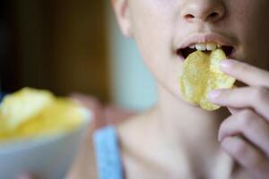 irreconhecível jovem menina comendo crocantes batata lasca foto