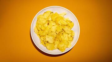 fechar-se do batata salgadinhos ou batatas fritas dentro tigela contra amarelo fundo foto