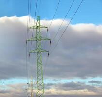 Alto Voltagem torres com elétrico fios em Sombrio nublado céu fundo. foto