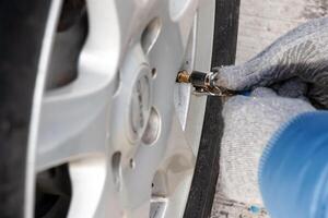 mão detém a pressão calibre e preenche a carro pneus com ar. carro manutenção. foto