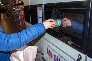 nitra, Eslováquia - 16.01.2024 fechar-se do uma do homem mão colocando uma garrafa para dentro uma desperdício reciclando máquina. foto