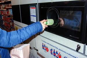 nitra, Eslováquia - 16.01.2024 fechar-se do uma do homem mão colocando uma garrafa para dentro uma desperdício reciclando máquina. foto