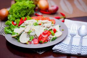 picante vidro macarrão salada com vietnamita linguiça servido dentro uma cinzento prato colocar em uma de madeira mesa e vários legumes. foto