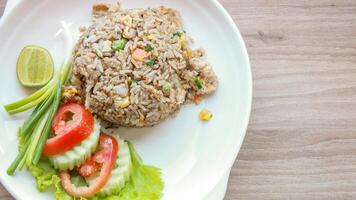 carne de porco frito arroz servido dentro uma restaurante com de madeira chão mesas com tomates, pepinos, cebolinha, frito arroz, delicioso Comida fez a partir de cozido no vapor arroz, topo Visão foto