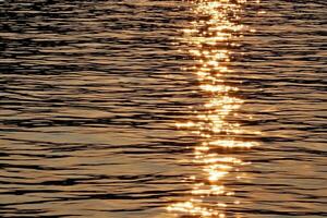 dourado pôr do sol luz em a superfície do a rio para fundo. foto