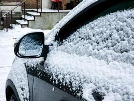 fechar-se do uma lado espelho do uma moderno carro coberto dentro neve foto