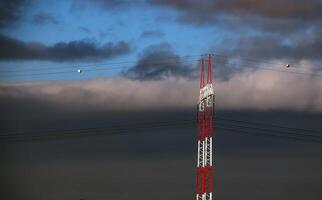 Alto Voltagem torres com elétrico fios em Sombrio nublado céu fundo. foto