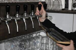 atrás a contador. mulheres mãos belas e facilmente derramar Cerveja para dentro uma garrafa. foto