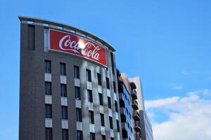 fukuoka, Japão novembro 14, 2023 coca Cola placa em a construção com azul céu fundo. a Coca Cola empresa, americano corporação fundado dentro 1892. foto