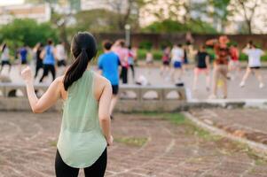 fêmea corredor. em forma jovem ásia mulher com verde roupa de esporte aeróbica dança exercício dentro parque e desfrutando uma saudável ar livre. ginástica corredor menina dentro público parque. bem estar ser conceito foto