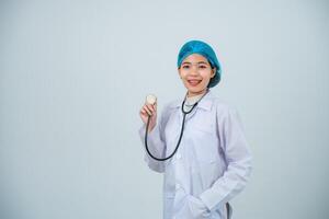 retrato ásia médico mulher, estagiário com segurando estetoscópio e médico manto, profissional, olhando confiante às Câmera, cinzento ou branco fundo. foto