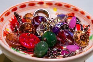 fechar-se foto do muitos colares e brincos dentro vários cores em uma pequeno tigela