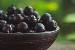 ai gerado fresco Açaí bagas tigela em natural verde fundo foto