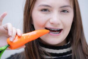 retrato do Adolescência menina comendo cenoura dentro dela dentes. foto