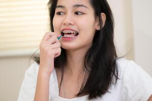 retrato do uma jovem ásia mulher com suspensórios em dela dentes foto
