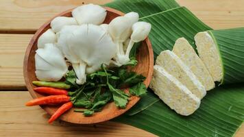 tempe fatias, ostra cogumelo, Pimenta em uma de madeira placa. tempeh ou tempe é a indonésio especialidade. vegetariano Comida. foto