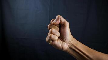 contando, agressão, bravo conceito. Preto masculino punho, cerrado mão, Forte masculino homem elevado punho poder, protesto, punho pronto para luta isolado em Preto fundo. foto