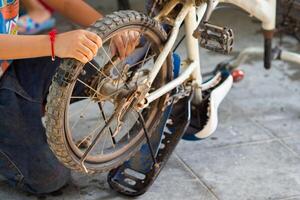 criança Garoto reparação dele bicicleta. foto