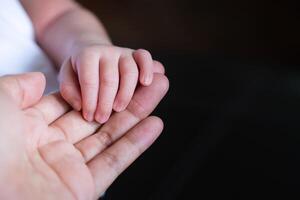 fechar-se do recém-nascido bebê mão dentro mão mãe foto