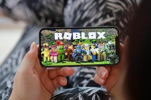 roblox Móvel ios jogos em Iphone 15 Smartphone tela dentro fêmea mãos durante Móvel jogabilidade foto